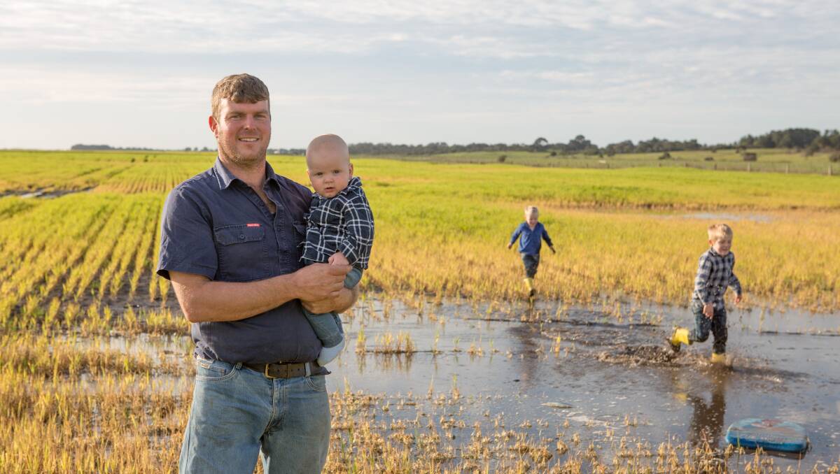 WET SITUATION: Andrew Skeer, Hatherleigh, holding son Joel in a field of waterlogged barley, while Leo and Kobe make the most of the situation in the lower South East.